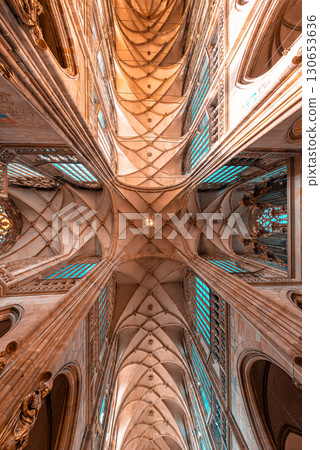 Sunlight shines through stained glass windows illuminating medieval gothic St. Vitus Cathedral vaulted ceiling. Prague, Czech Republic Sunlight shines through stained glass windows illuminating medieval gothic St. Vitus Cathedral vaulted ceiling. Prague, Czech Republic 130653636