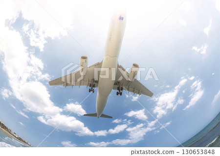 Passenger airplane flying low over beach before landing 130653848