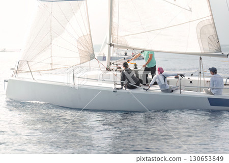 Team of sailors maneuvering on sailboat during regatta Team of sailors maneuvering on sailboat during regatta 130653849