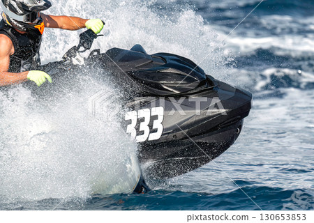 Professional jet ski racer turning at high speed leaving water trail Professional jet ski racer turning at high speed leaving water trail 130653853