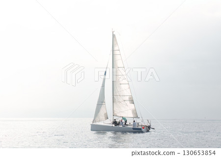 Sailing team adjusting sails on yacht during regatta on calm sea 130653854