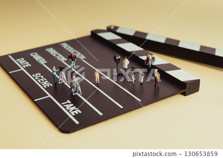 Miniature film crew working on movie set with clapperboard Miniature film crew working on movie set with clapperboard 130653859