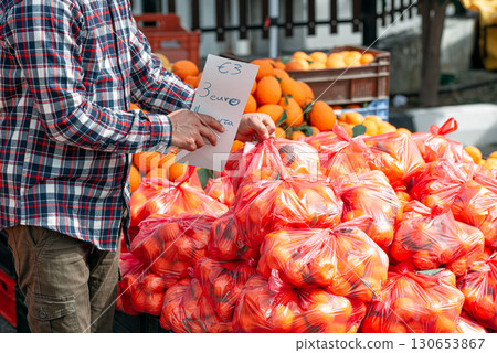 Street vendor holding price tag for oranges at outdoor market Street vendor holding price tag for oranges at outdoor market 130653867
