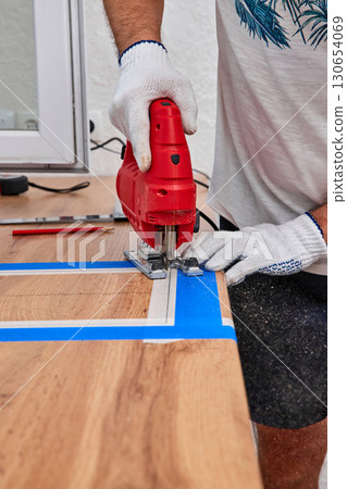 repairman using electric jigsaw and cutting hole for the sink in the kitchen countertops 130654069