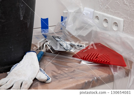 wall repair tools. putty knives , plaster bucket, gloves on kitchen countertop. renovation work 130654081