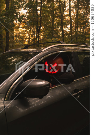 Autumn SUV with Driver with Pumpkin Head in Forest Autumn SUV with Driver with Pumpkin Head in Forest 130654089