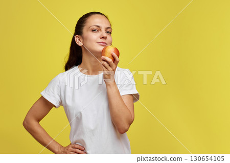Portrait of happy woman holding apple isolated over yellow background Portrait of happy woman holding apple isolated over yellow background 130654105