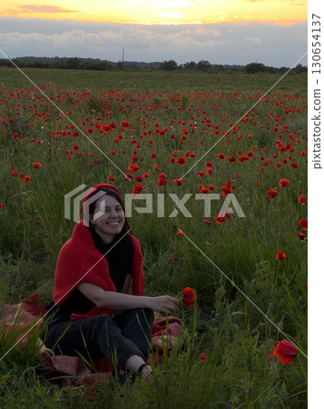 Young Woman in Poppy Field with Red Hat 130654137