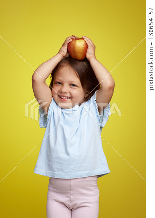 cute Caucasian little child girl holding apple on yellow background cute Caucasian little child girl holding apple on yellow background 130654152