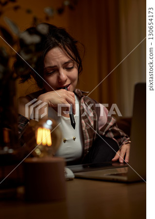 tired graphic designer woman working at home office remotely using digital graphic tablet and laptop tired graphic designer woman working at home office remotely using digital graphic tablet and laptop 130654173