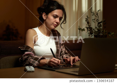 beautiful graphic designer woman working at home office remotely using digital graphic tablet with stylus and laptop 130654187