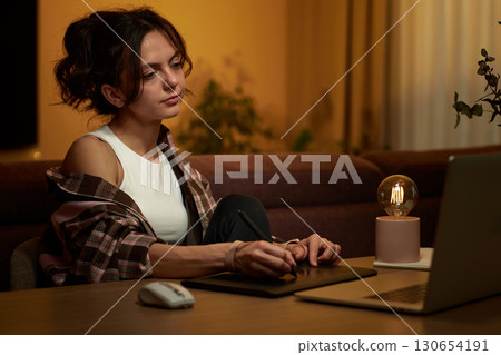 beautiful graphic designer woman working at home office remotely using digital graphic tablet and laptop beautiful graphic designer woman working at home office remotely using digital graphic tablet and laptop 130654191