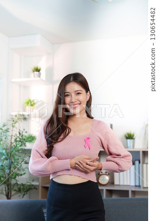 Breast Cancer Awareness. Young woman holding pink ribbon symbolizing support and hope. 130654482