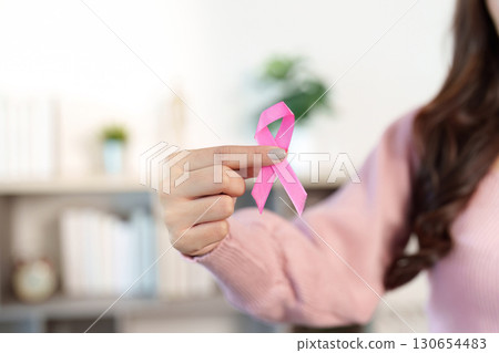 Breast Cancer Awareness. Close-up of pink ribbon held by a woman, symbolizing hope and support. Breast Cancer Awareness. Close-up of pink ribbon held by a woman, symbolizing hope and support. 130654483