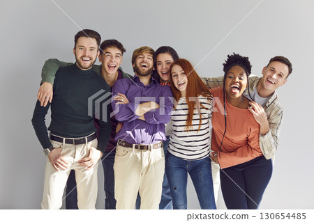 Joyful happy people friends looking cheerful at camera on a grey wall background. Joyful happy people friends looking cheerful at camera on a grey wall background. 130654485