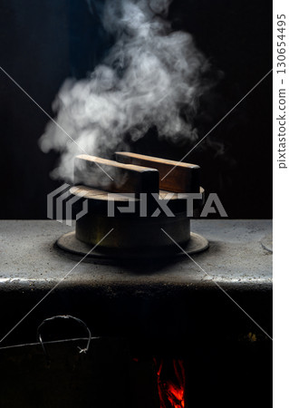 Steam and flames flicker from the hearth of an old house 130654495