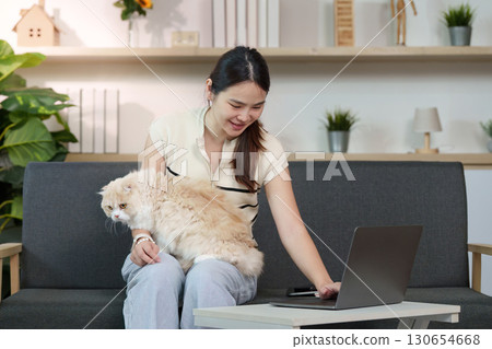 Remote Work with Pet. Young woman enjoying work from home lifestyle with her cat. Remote Work with Pet. Young woman enjoying work from home lifestyle with her cat. 130654668