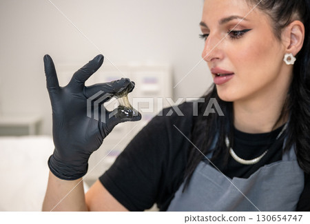 Beautician woman in black gloves holding sugaring paste for professional hair removal 130654747