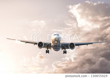 Modern passenger airplane flying in cloudy sky at sunset Modern passenger airplane flying in cloudy sky at sunset 130655029
