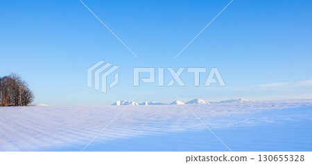 A snowy winter landscape in Biei, Hokkaido, with a view of the blue sky and the Tokachi mountain range 130655328