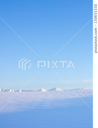 A snowy winter landscape in Biei, Hokkaido, with a view of the blue sky and the Tokachi mountain range 130655338