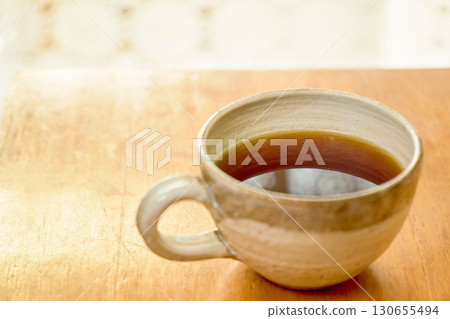 一杯咖啡和蕾絲窗簾輪廓的特寫。 130655494