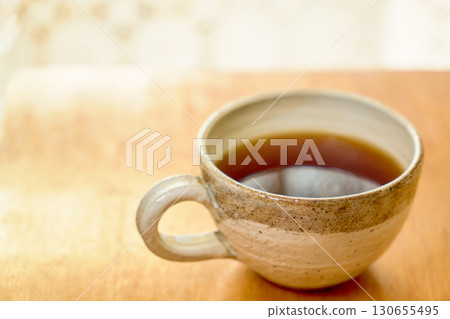 一杯咖啡和蕾絲窗簾輪廓的特寫。 一杯咖啡和蕾絲窗簾輪廓的特寫。 130655495