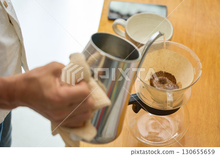 A man pours the first steaming water. A series of photos showing the process of brewing coffee using a paper drip. 130655659