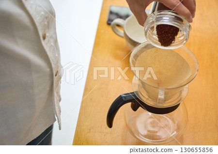 一位男士將磨好的咖啡豆倒入滴濾壺。一系列照片展示了滴濾咖啡的沖泡過程。 一位男士將磨好的咖啡豆倒入滴濾壺。一系列照片展示了滴濾咖啡的沖泡過程。 130655856