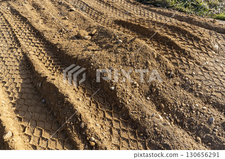 tracks in the sand on a part of the road in a field, sand on the road in a field with traces of agricultural or construction vehicles 130656291