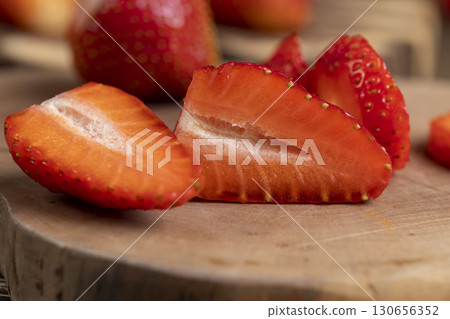several sliced red ripe strawberries, ripe sweet and juicy strawberries cut into pieces on a wooden table 130656352