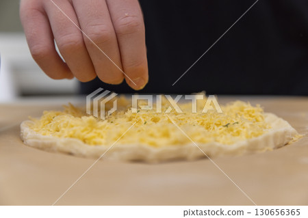 cheese tortilla made of yeast dough and grated cheese, thinly rolled dough sprinkled with yellow hard grated cheese 130656365