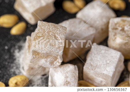 Turkish delight cubes and toasted peanuts on a black slate surface, closeup 130656367