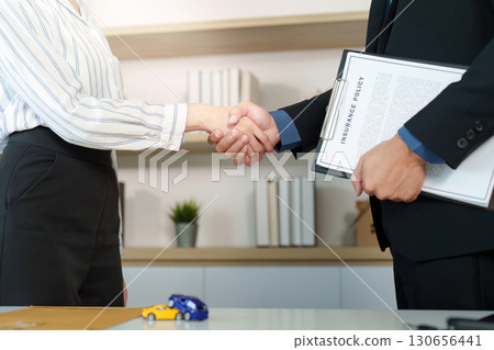 Insurance Agreement. Client and agent shaking hands after signing policy. Insurance Agreement. Client and agent shaking hands after signing policy. 130656441