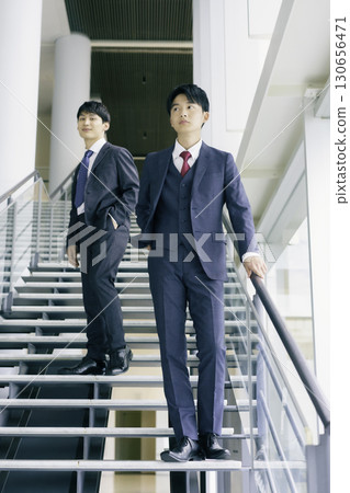 Portrait of two young businessmen standing on the stairs of an office building, vertical position 130656471