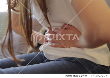 Image of a woman with abdominal pain holding her stomach Image of a woman with abdominal pain holding her stomach 130657224