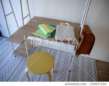 A desk, a school bag, textbooks, and a yellow chair 130657244