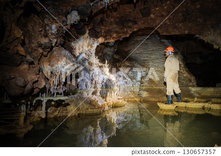 A speleologist explores a majestic cave, illuminated by a headlamp 130657357