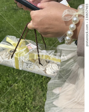 Woman holding a marshmallow in a gift box in her hand. Close-up. Woman holding a marshmallow in a gift box in her hand. Close-up. 130657403