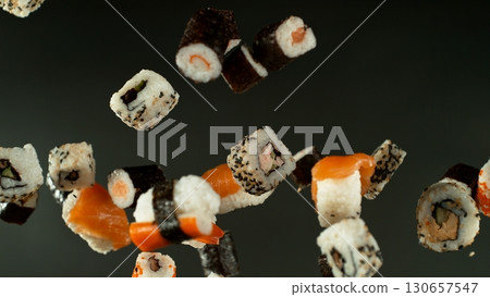Freeze motion of flying sushi pieces on black background. Concept of flying japanese traditional food. Studio shot, dark background. 130657547
