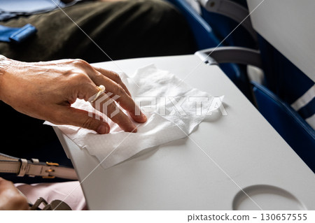 Air travel passenger wiping airplane table with anti-bacterial wet wipes Air travel passenger wiping airplane table with anti-bacterial wet wipes 130657555