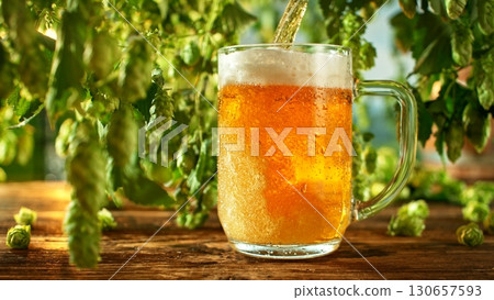 Pouring Beer into Glass with Hops Plants , Close-up 130657593