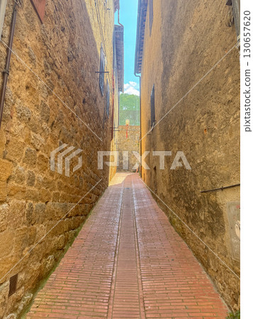 Narrow stone alleyway with quaint brick path leading through historic village. Rustic charm of ancient architecture creates a serene and timeless passageway. Ideal for travel themes. Italy, San Narrow stone alleyway with quaint brick path leading through historic village. Rustic charm of ancient architecture creates a serene and timeless passageway. Ideal for travel themes. Italy, San 130657620