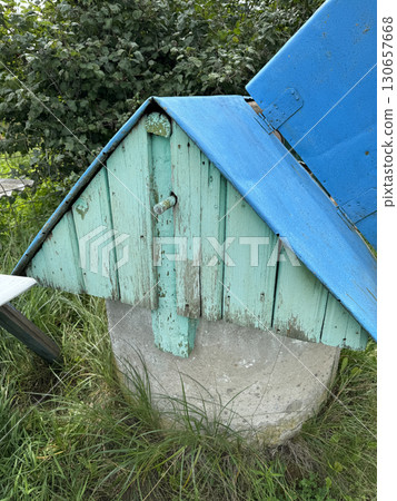 Well in a village. House-shaped lid over a mine shaft well. 130657668