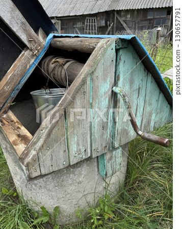 Well in a village. House-shaped lid over a mine shaft well. Well in a village. House-shaped lid over a mine shaft well. 130657791