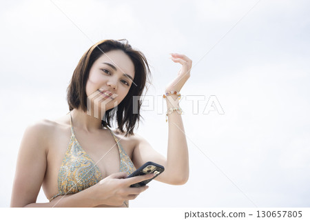 Young woman in a swimsuit looking at the sea Young woman in a swimsuit looking at the sea 130657805
