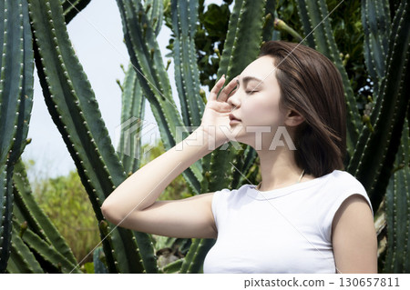 Beautiful woman standing in front of a cactus 130657811