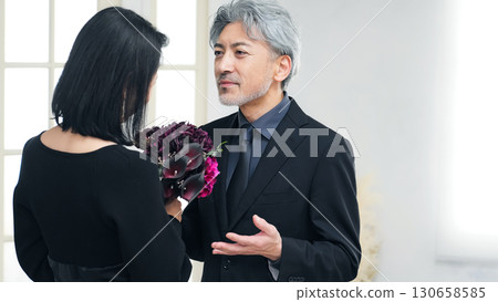 Middle-aged couple handing over a bouquet 130658585