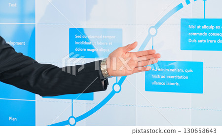 A male business person giving an explanation in front of a large screen monitor A male business person giving an explanation in front of a large screen monitor 130658643