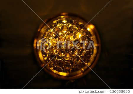 Fish Oil Omega-3 Capsules in Glass Container with Golden Glow 130658990